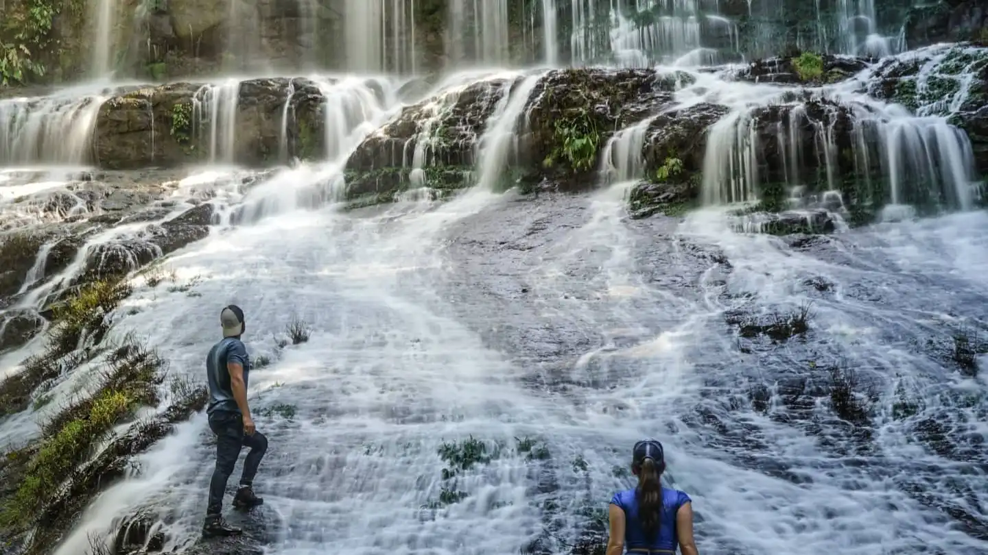 Zwei Menschen stehen vor einem Wasserfall