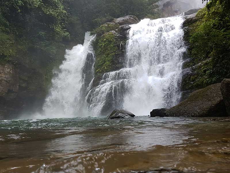 Ein Mann steht in einem Fluss neben einem Wasserfall.
