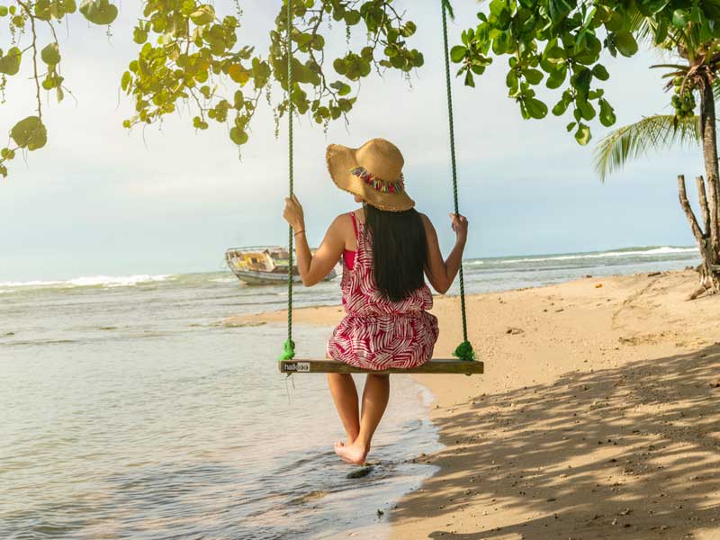 Eine Frau sitzt auf einer Schaukel am Strand.