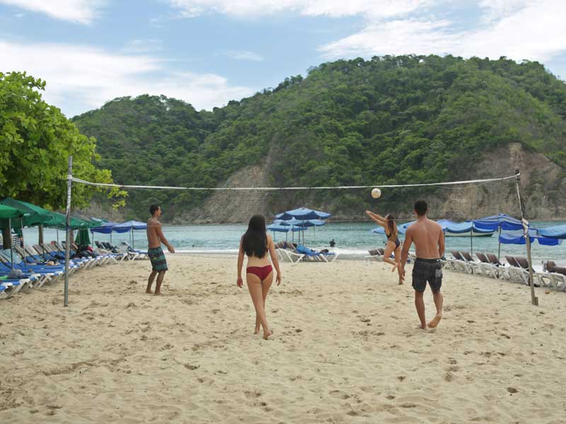 Eine Gruppe von Menschen spielt Volleyball am Strand.