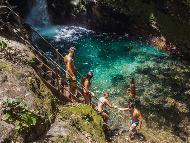 Eine Gruppe von Menschen steht oben auf einer Klippe neben einem Wasserfall.