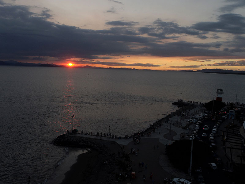 Eine große Wasserfläche mit einem Sonnenuntergang im Hintergrund.