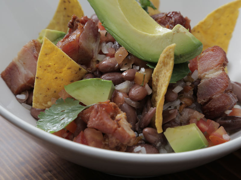 Eine weiße Schale, gefüllt mit Bohnen, Fleisch und Avocado.