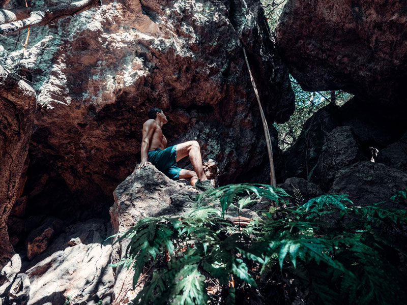 Ein Mann sitzt auf einem Felsen am Rande eines Waldes.