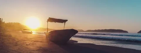 Der Anblick des Sonnenuntergangs und des Meeres, während das Boot am Strand lag