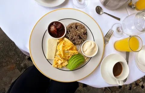Ein Teller mit Frühstücksspeisen auf einem Tisch, dazu Kaffee und Orangensaft