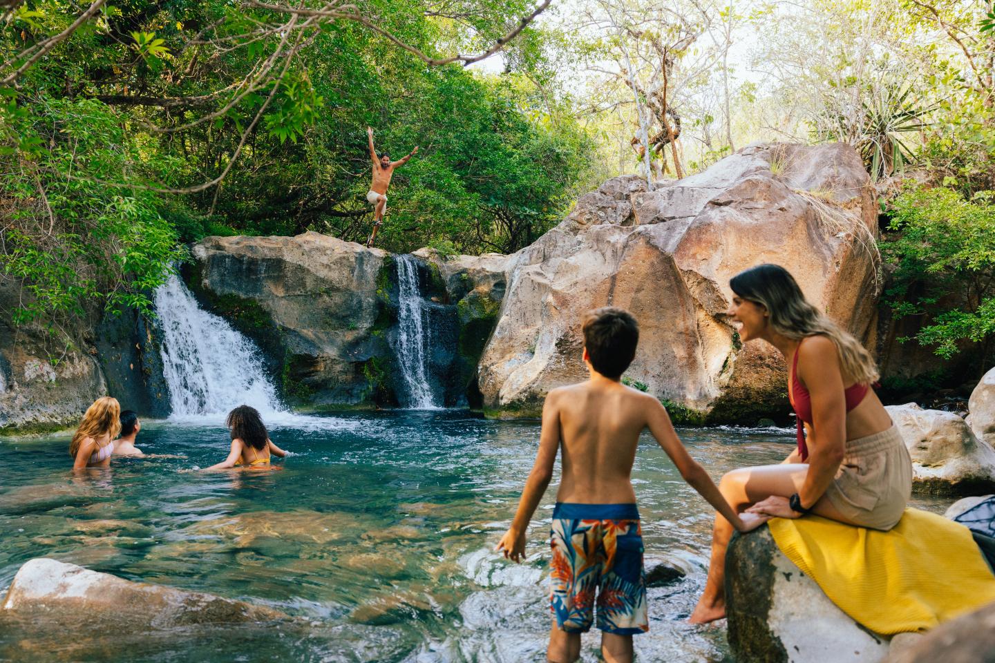 Familie schwimmt in einer Quelle im Dschungel